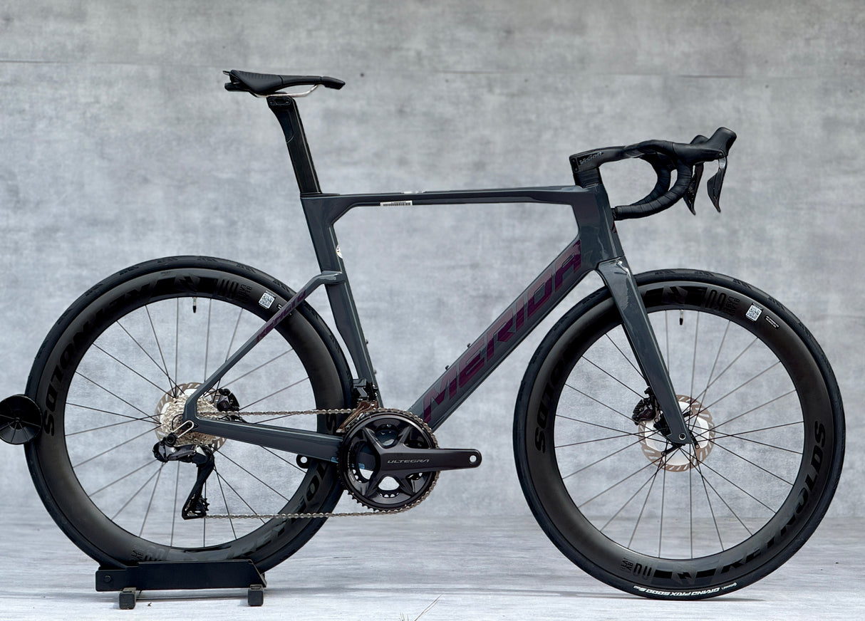 Merida Reacto 9000 2025 – High-End Aero Racefiets
De Merida Reacto 9000 2025 is dé keuze voor wielrenners die maximale snelheid en efficiëntie eisen. Met een ultralicht CF5 carbon aero-frame, aerodynamische buisvormen en geïntegreerde kabelgeleiding is deze fiets gebouwd om wind te verslaan.
De fiets is afgemonteerd met de nieuwste Shimano Dura-Ace Di2 12-speed groepset, wat zorgt voor razendsnelle en nauwkeurige elektronische schakelingen. De krachtige hydraulische schijfremmen bieden maximale controle,
